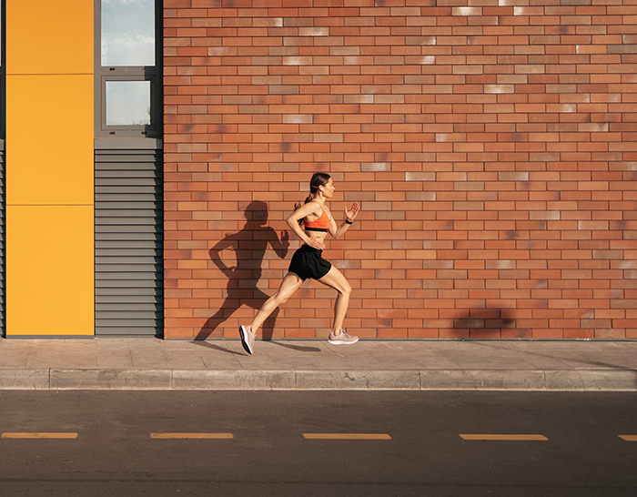 Young woman sprinting in the morning outdoors. Side view of female runner working out in the city.
