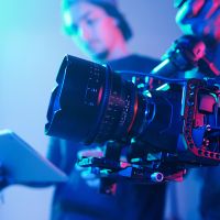 Close-up of operator using professional camera during shooting with director controlling the process