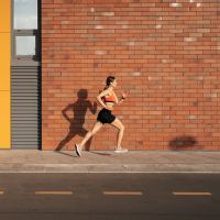 Young woman sprinting in the morning outdoors. Side view of female runner working out in the city.